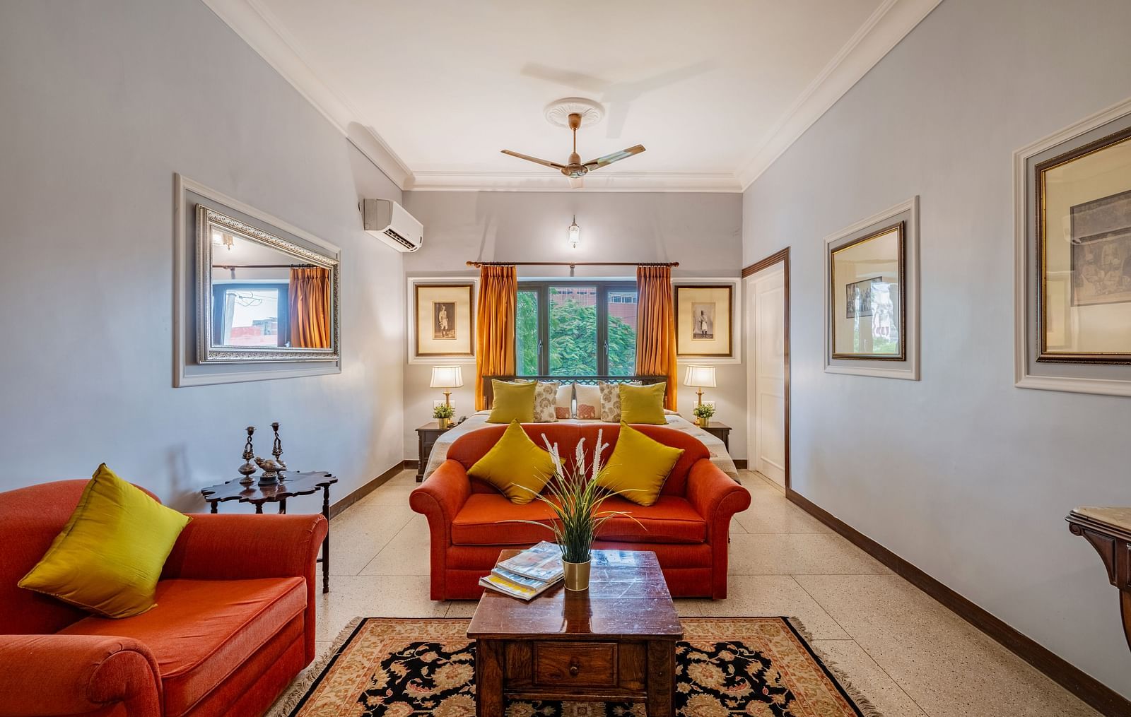 A spacious and elegant suite at Dera Rawatsar  in Jaipur offers comfortable seating areas, a wooden coffee table, and a glimpse of the inviting bed.