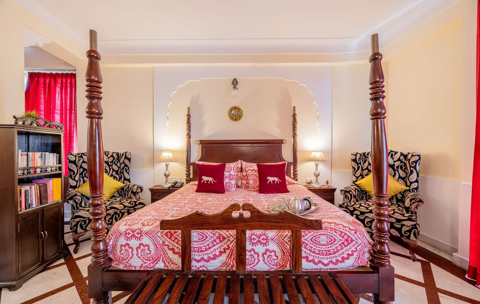 A bedroom with a four-poster bed, patterned bedding, and ornate armchairs | Dera Rawatsar, Jaipur