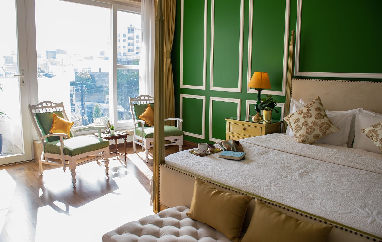 A room at Dileep Kothi, Jaipur with a double bed and a coffee table arrangement placed in front of a sliding door