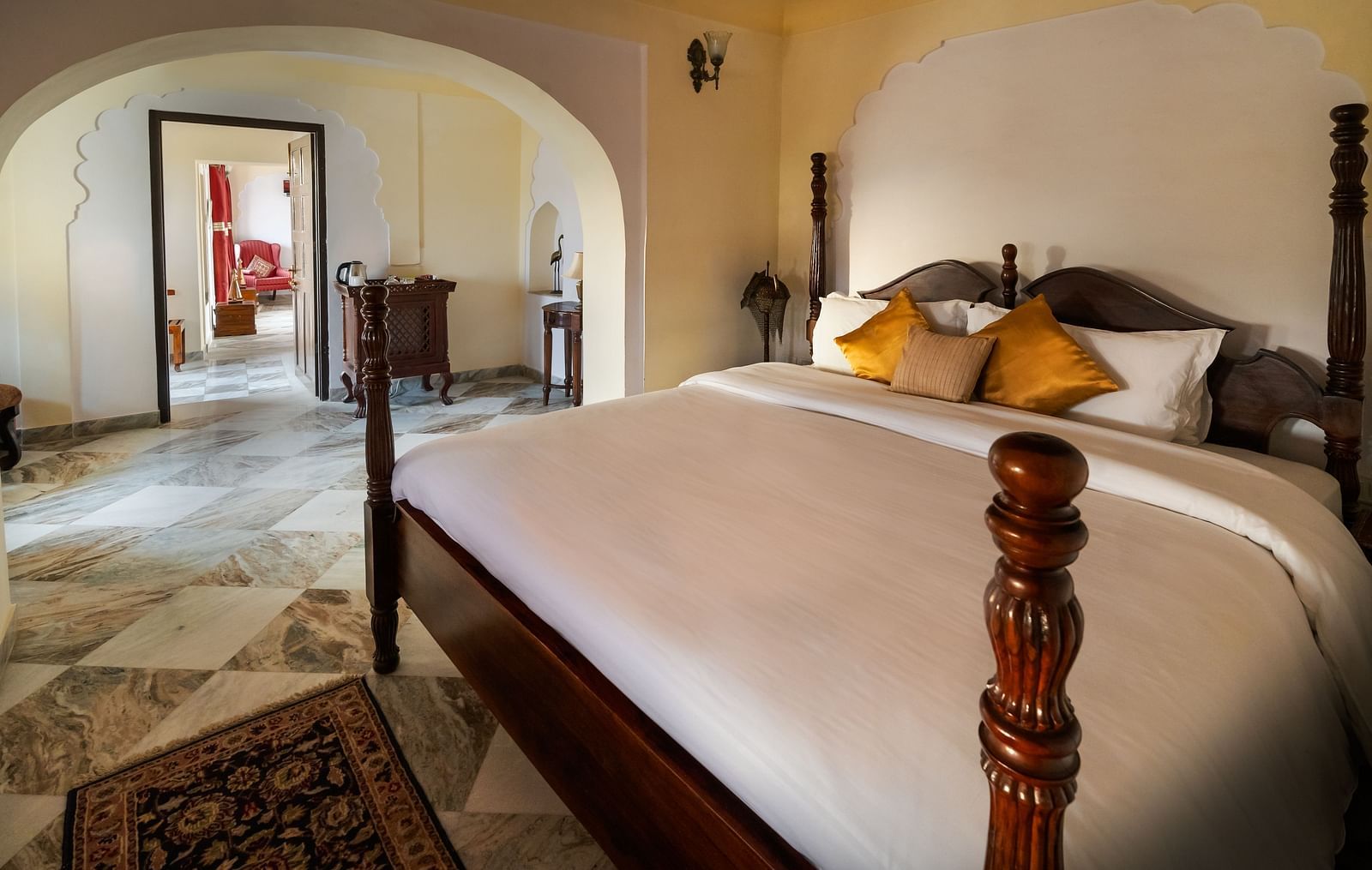 A four-poster bed dominates a room at Fort Barli, Ajmer, with arched doorways leading to other areas.