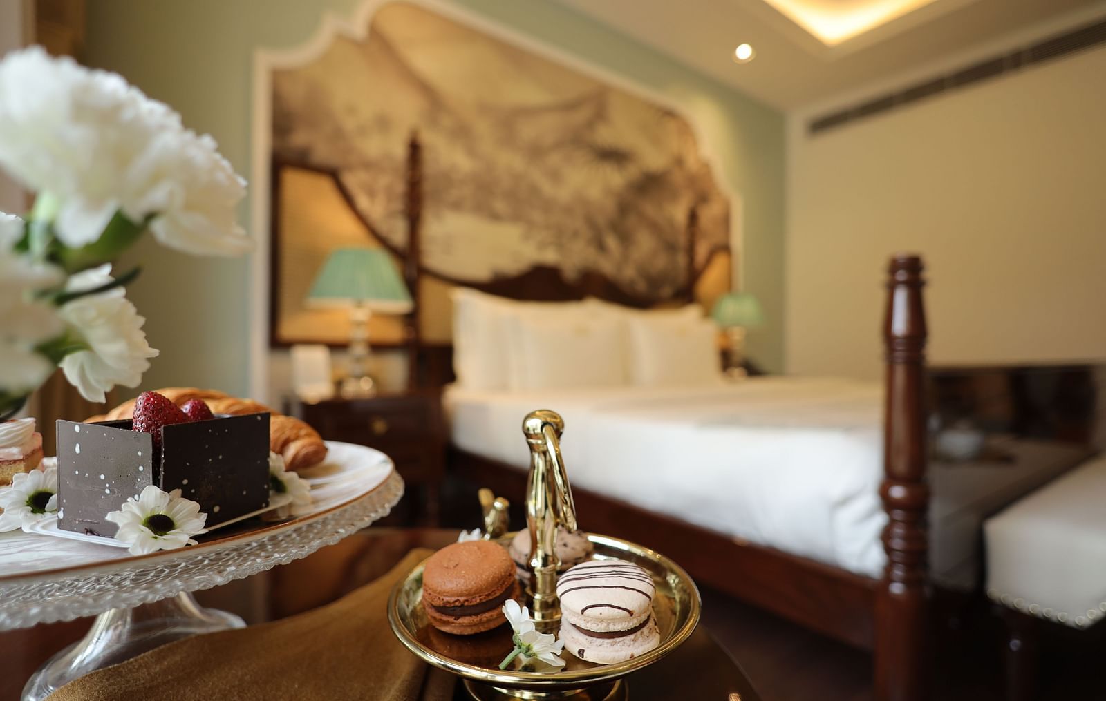 A plate of macaroons placed on the coffee table in a room at The Umaid Vilas, Jaipur with the double bed in the backdrop