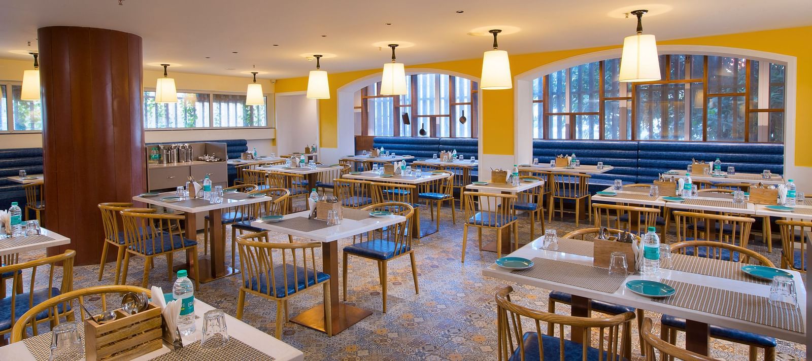 A bright and inviting restaurant interior with yellow walls, pendant lights and blue booth seating - Hotel Southend by TGI - Bommasandra, Bangalore