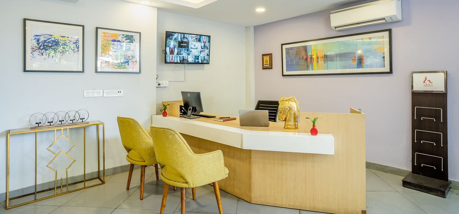 An image of a reception of the hotel where a desk and two chairs are placed | Inde Hotel Golf Course Extension