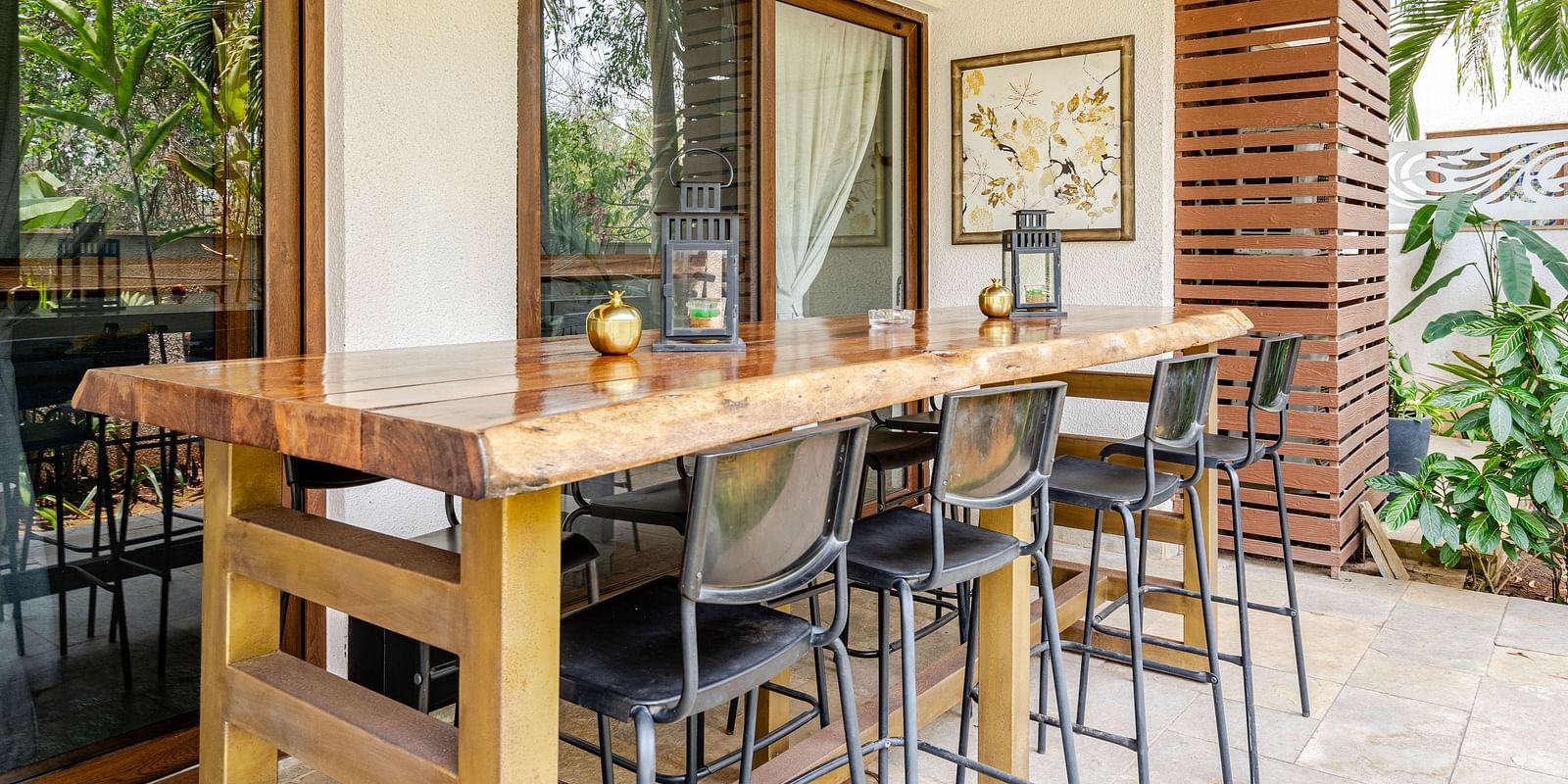 Outdoor dining space at Lindsay Manor with a long wooden table, high chairs, and greenery in the background.