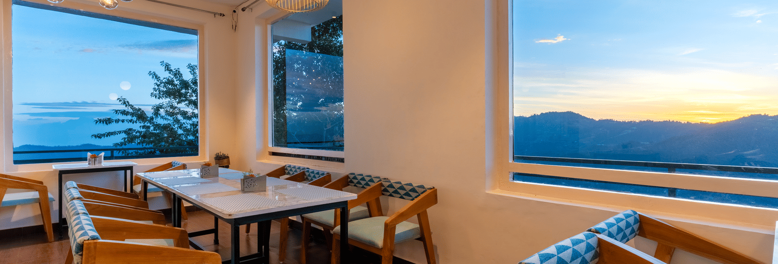 A view of the sunlit dining area with wooden furniture at Himalayas Resort By The Lake Hill, Mukteshwar during sunset.