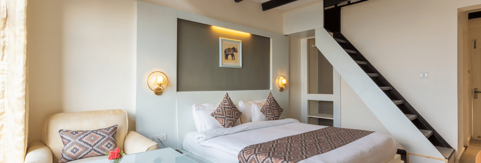 A high-angle view of a guest room with dark wooden ceiling beams and a staircase at Himalayas Resort By The Lake Hill, Mukteshwar.