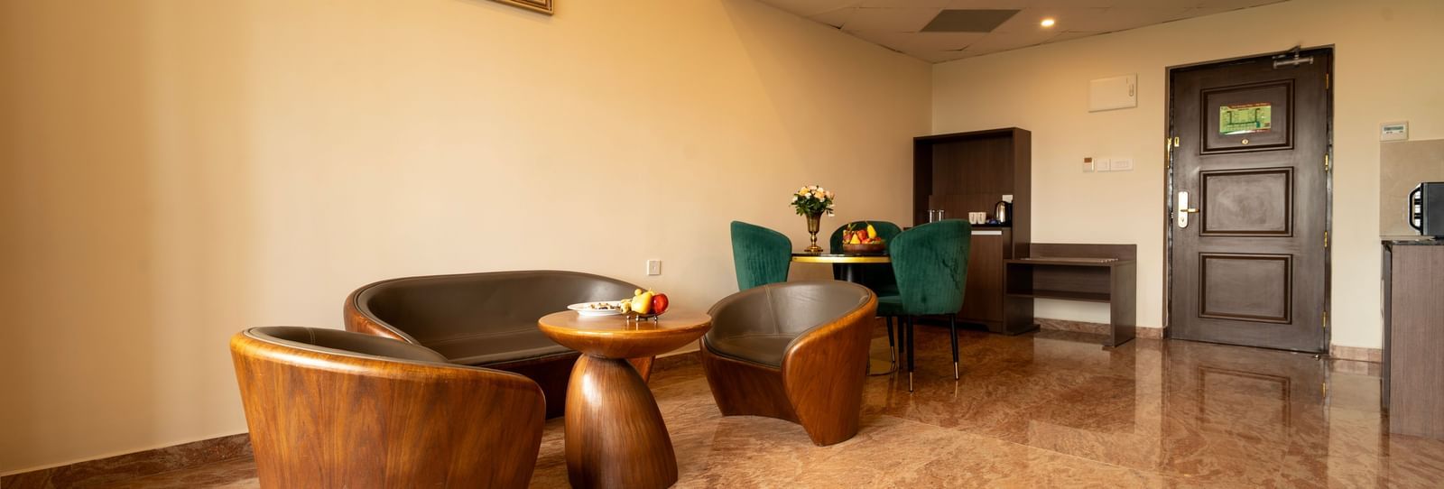 A marble-floored living room in our hotel accommodation in chennai featuring a coffee table, arm chairs, a love seat and a work desk - Accord Chrome Airport Hotel