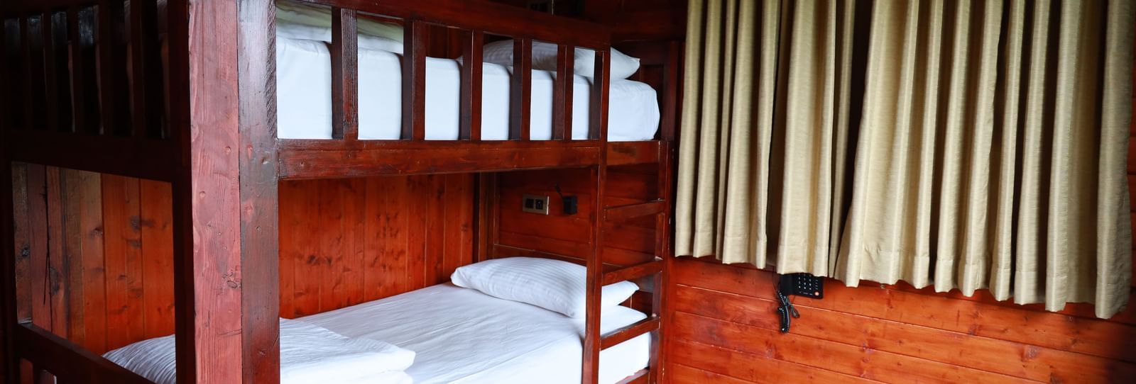 Bunk bed featuring wooden frame, plush mattress placed near a window - Accord Highland Ooty