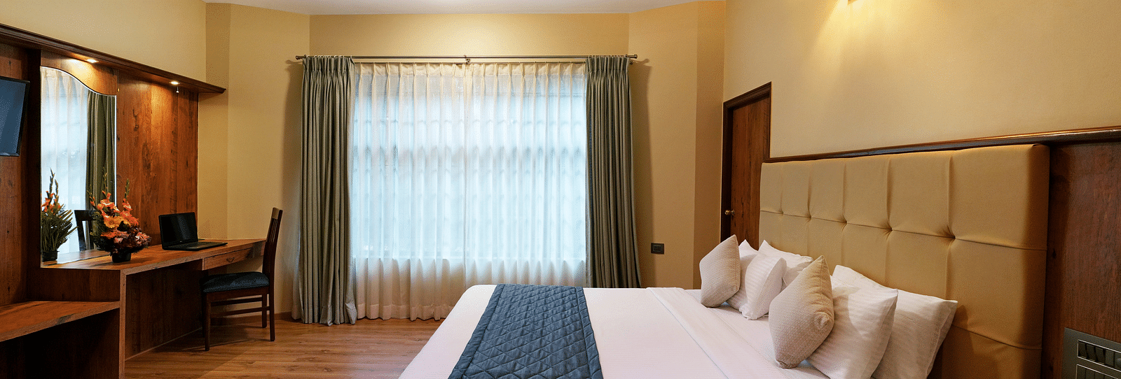 An Executive Room with a large bed, wooden decor, and natural light - Cross Roads Inn, Bengaluru