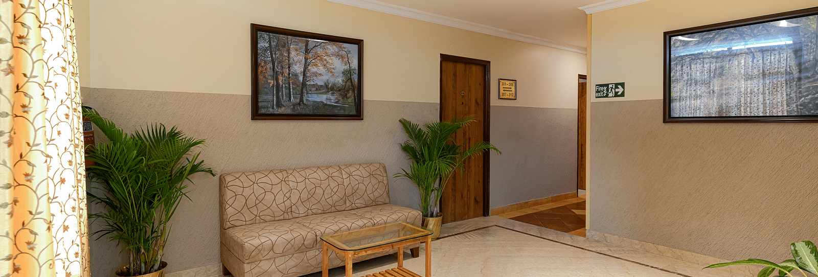 A lobby area with a couch and potted plants - Cross Roads Inn, Bengaluru