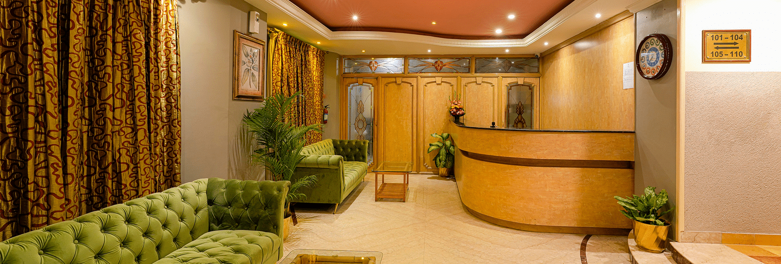 A cosy reception area with green couches and warm lighting - Cross Roads Inn, Bengaluru