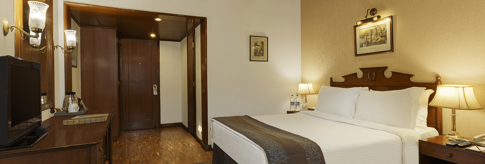 An interior view of the room with bed, television, wooden flooring and roofing - Leisure Hotels