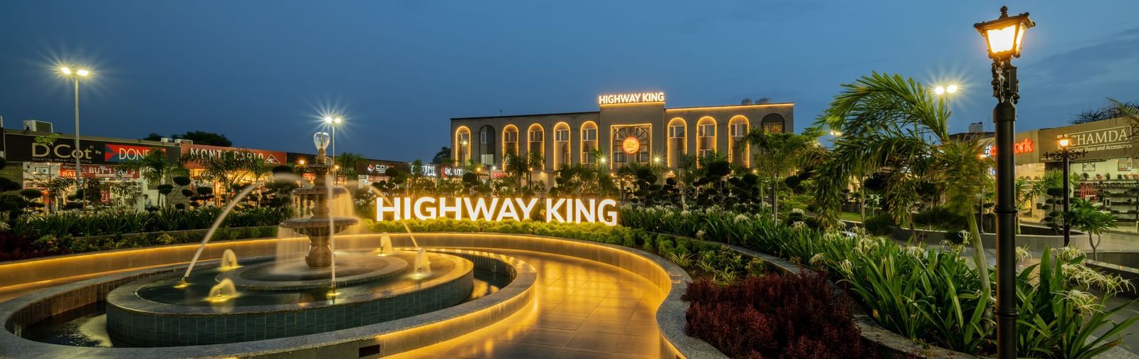 Facade view of Hotel Highway King, Neemrana, featuring a fountain a few yards in front of the building and warm lighting around the area. 
