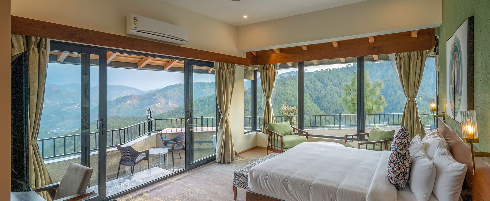Spacious room with a large bed and a large glass sliding door leading to a balcony with a mountain view at The Chamomile Estate.