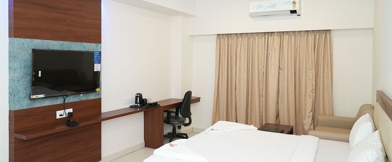 full view image of the room overlooking two plush double beds facing towards the wall mounted television with a work desk and chair in the corner - Hotel Grand Sigma