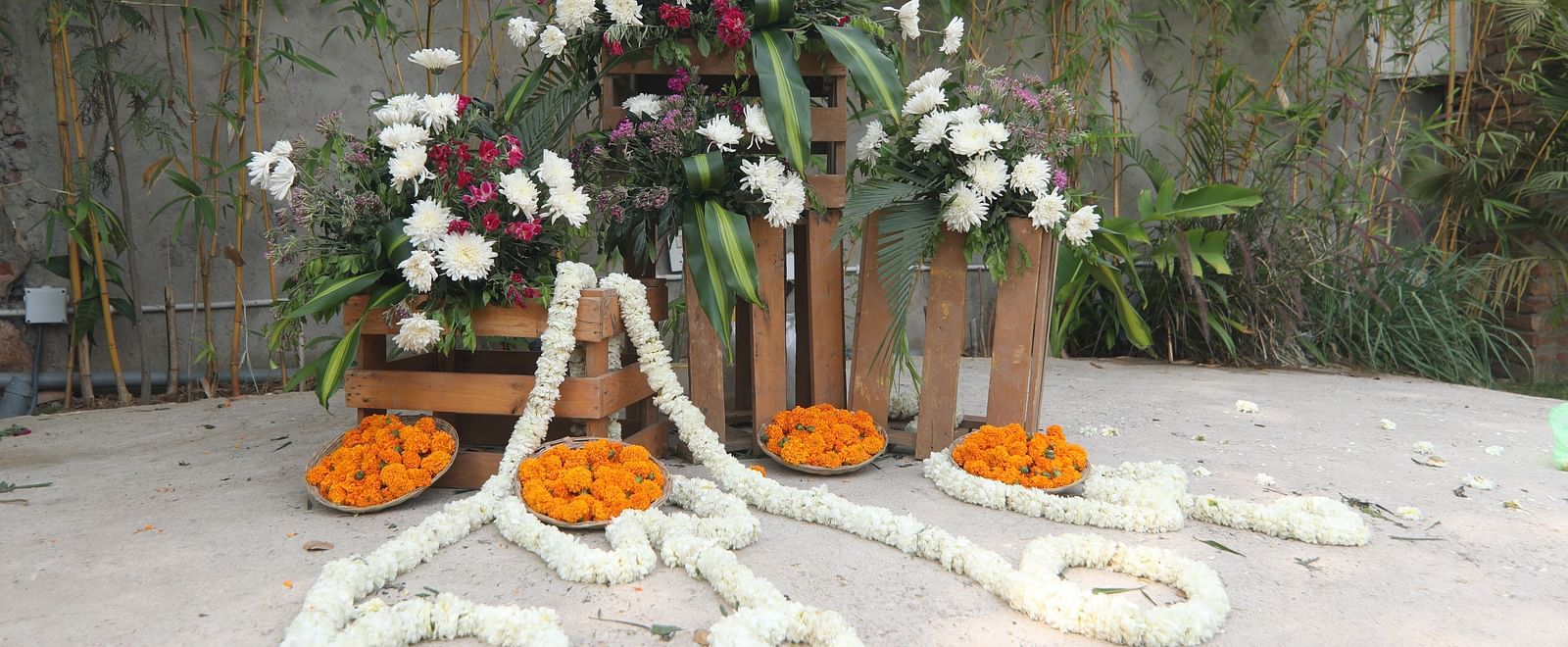 Wedding setup at Tisya Farms, Gurgaon with white garlands, orange marigolds, and red floral pillars.
