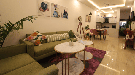 A long open living space, featuring an olive green sofa in the foreground, with a dining area visible in the background, all connected by a purple rug | Perfectstayz Value Homes, Mussoorie