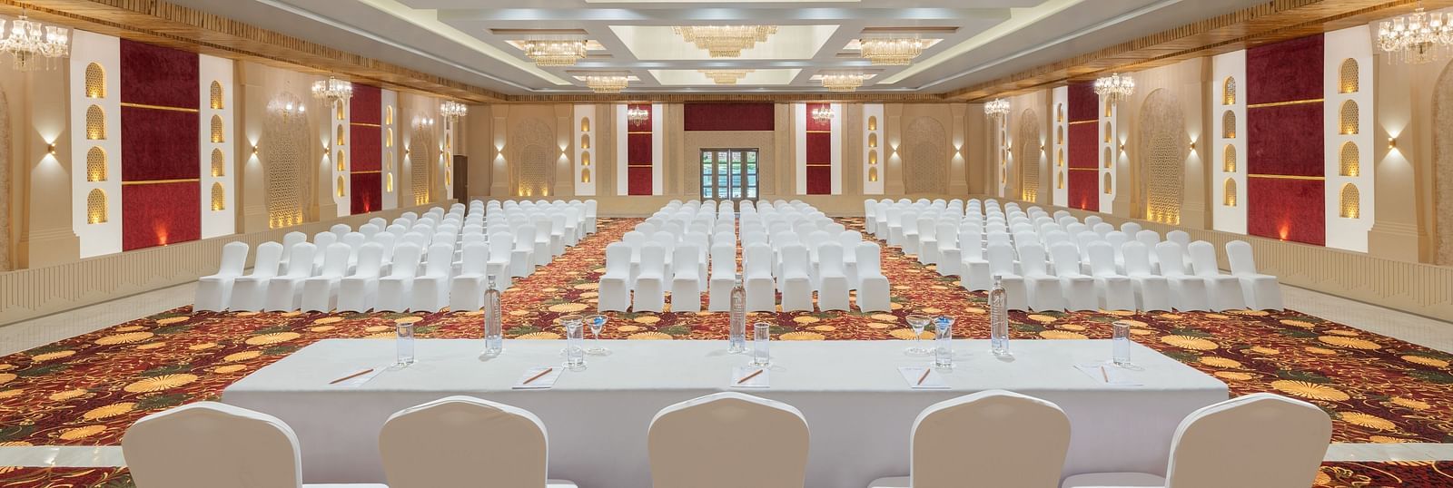 Grand Ballroom banquet with chair setting facing towards the stage with a group of chairs placed in front of a single table at A dining setting of Blue Salt and Coffee at Essentia Luxury Resort & Spa, Udaipur.. 