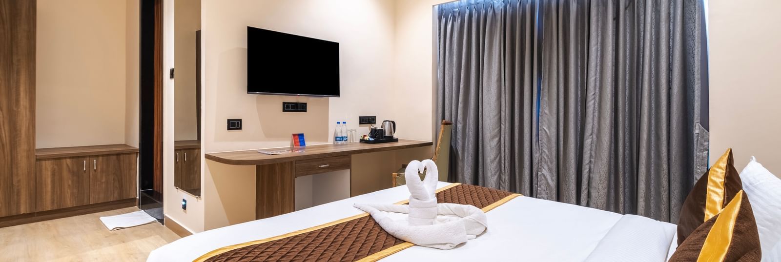 Spacious room at Monday Hotels Amalapuram Heights with TV, curtains, and double bed.