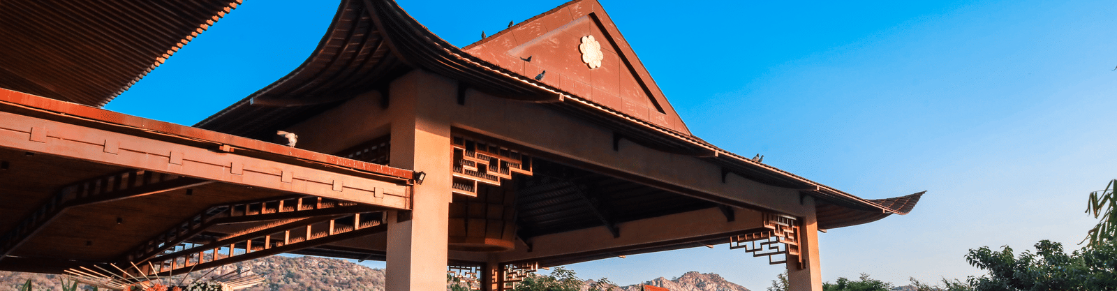 The exterior entrance of Ananta Spa & Resort, Jaipur, showcases its distinctive pagoda-style architecture against a bright blue sky.