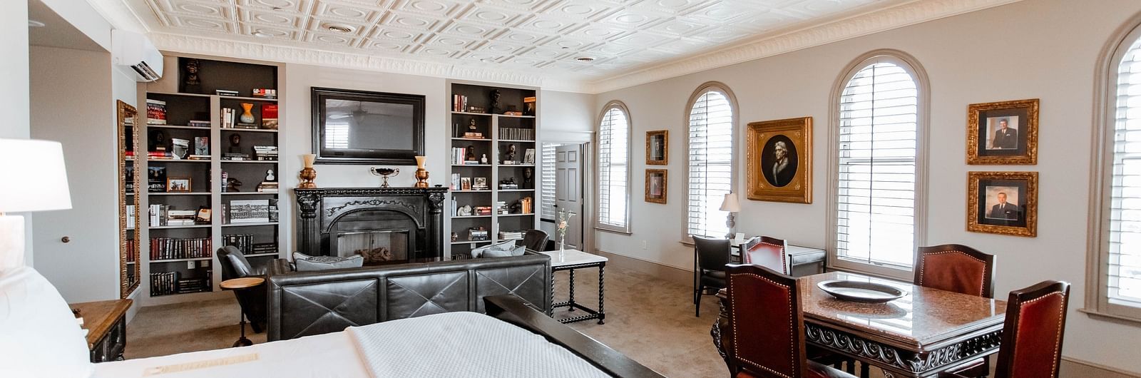 A large bedroom featuring a bookshelf with books, a cosy seating area, and a comfortable bed, providing a relaxing environment - The Grand Hotel & Ballroom, McKinney