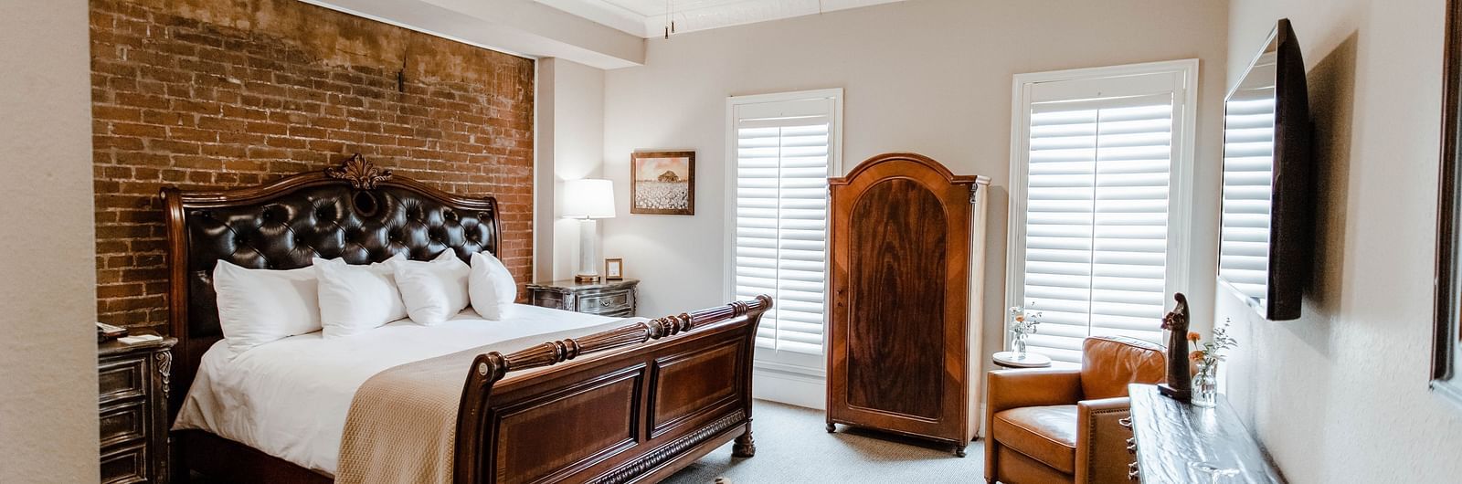 A spacious bedroom with a leather chair, modern decor, and a large bed, creating a stylish and comfortable living space - The Grand Hotel & Ballroom, McKinney