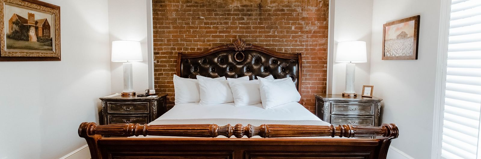  A classic bedroom with dark wood furniture, a large bed, and soft, natural lighting from the window, providing a serene retreat - The Grand Hotel & Ballroom, McKinney