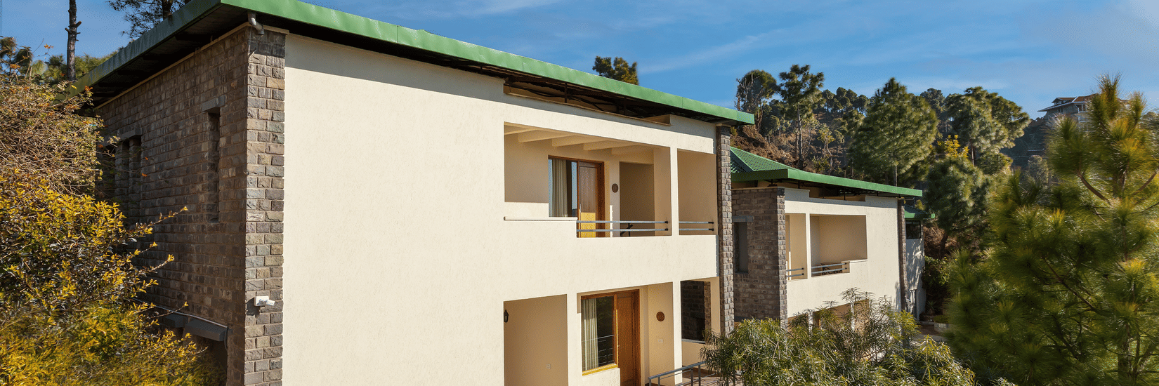 Facade of a 2-storey building in the premises of Suryavilas Luxury Resort and Spa on a sunny day amidst trees