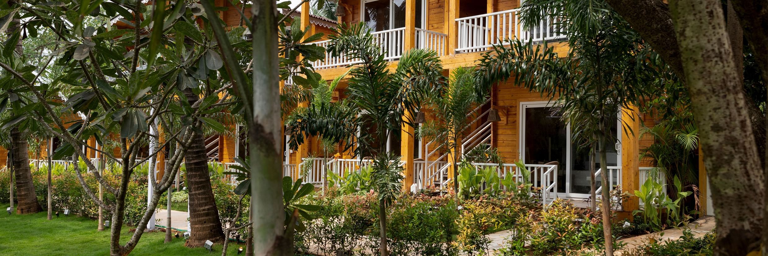 cottage facade with grass area in the foreground that has trees on it - Aralea Beach Resort by Stone Wood, Morjim