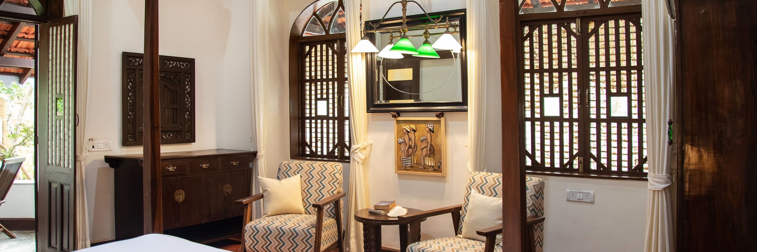 An image of a bedroom featuring a bed, a wardrobe, a work desk and chair, and two vintage styel windowds - Lamrin Ucassaim Hotel, Goa