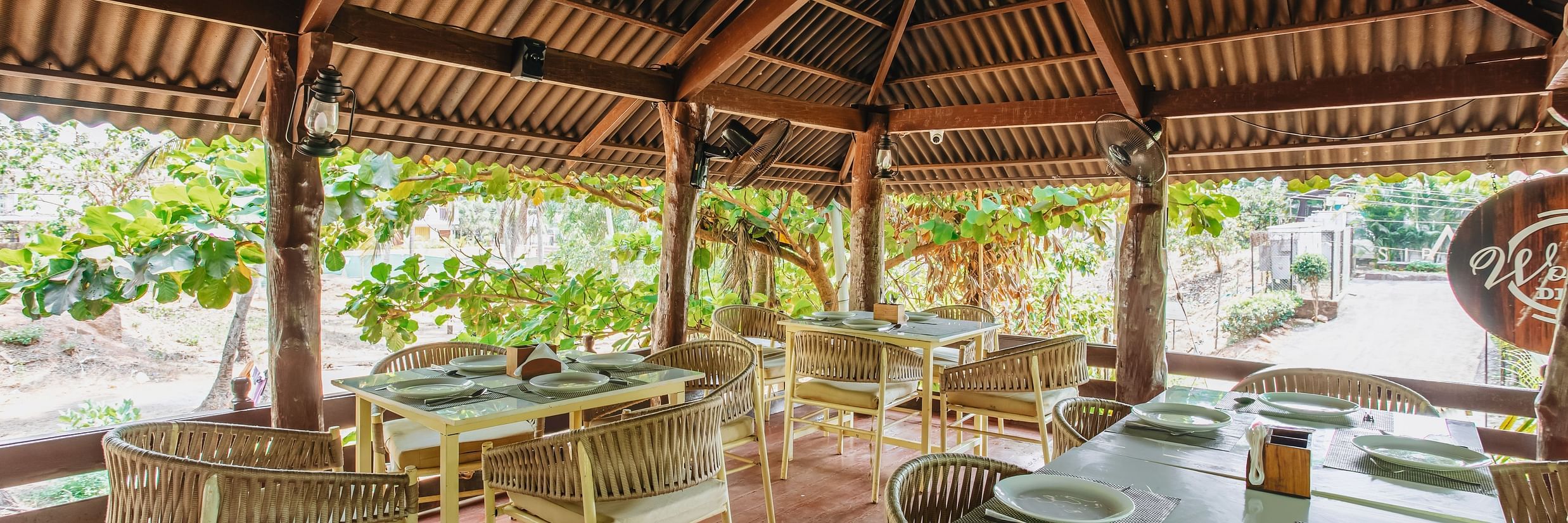 image of the wooden deck with covered seating arrangement surrounded by lush tropical greenery at sibaya beach resort, morjim beach