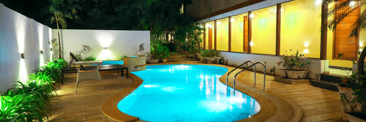 An overview of the swimming pool with lights on in the night - Rosetum Anjuna.