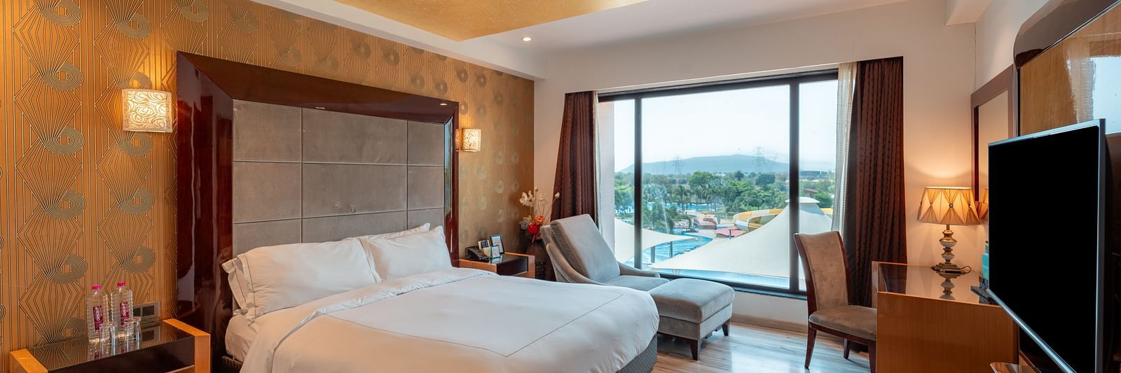 Family Suite includes a spacious bed with a bedside table, large windows, and a wall-mounted television at Crescent Spa & Resort, Indore