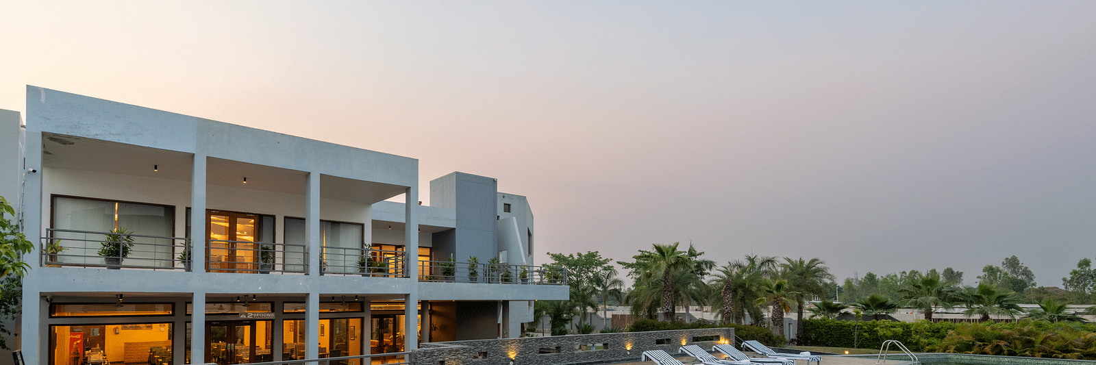 Facade view of DLS Forest Vines Resort on one side and the pool on the other, set against the sky.