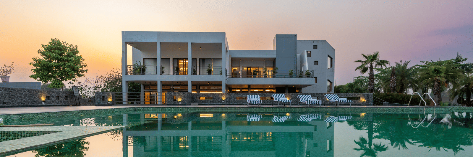 Facade view of DLS Forest Vines Resort with its reflection shimmering on the swimming pool under a clear sky.