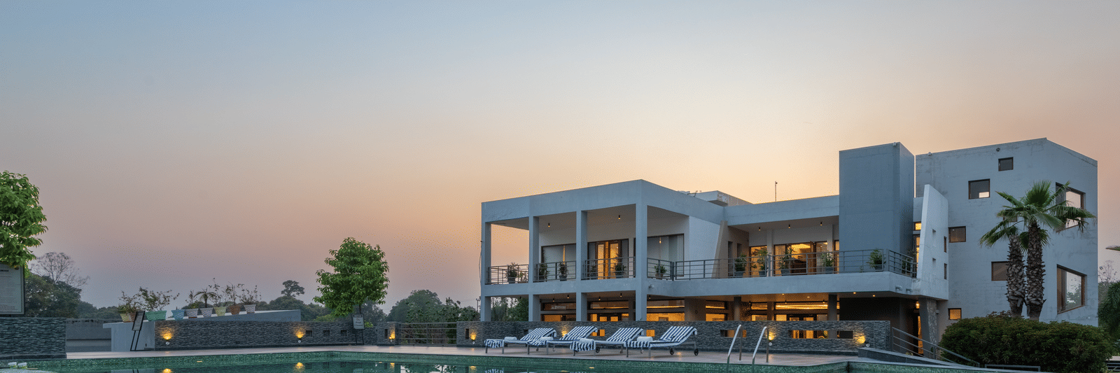 Facade view of DLS Forest Vines Resort with its reflection shimmering on the swimming pool under a clear sky.