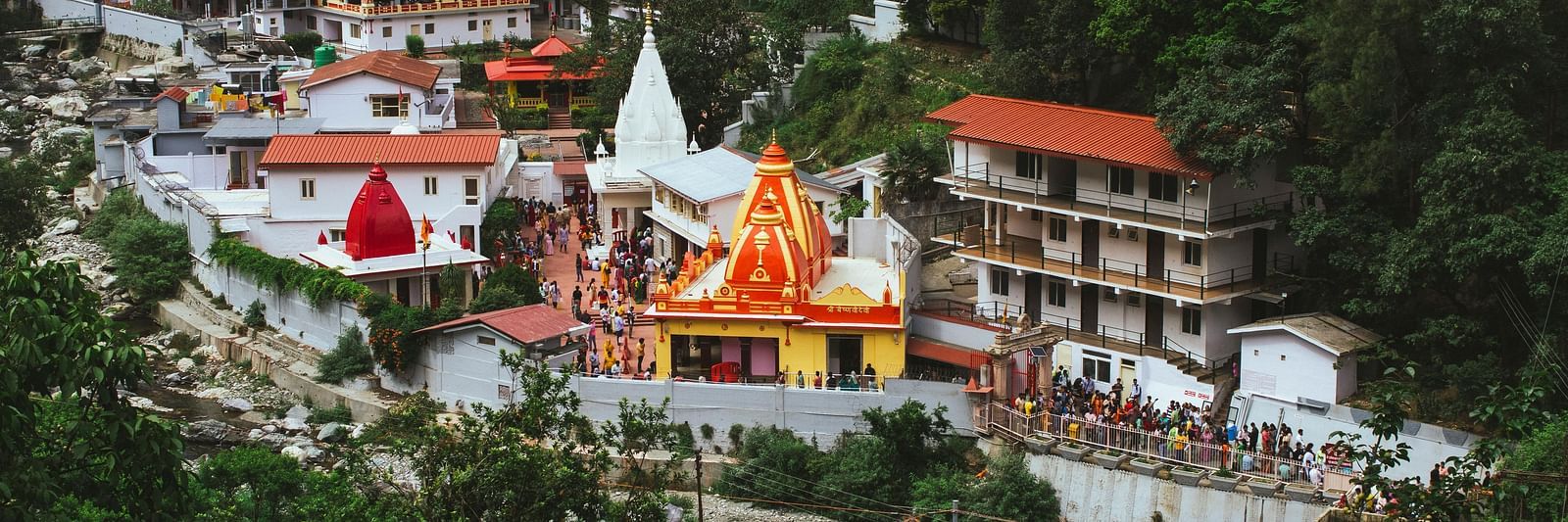 image featuring a bright yellow and red coloured temple in Nainital amidst various other buildings