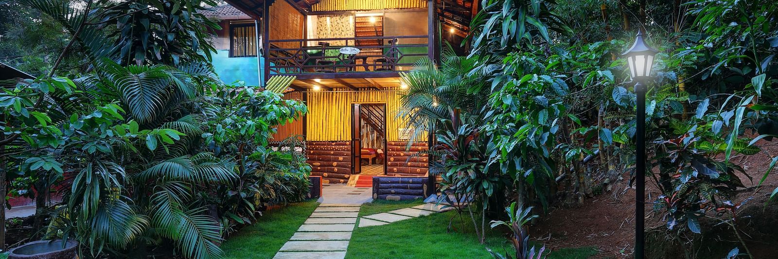 A facade image of the Group Wooden Cottage covered in lush green trees - Evergreen County