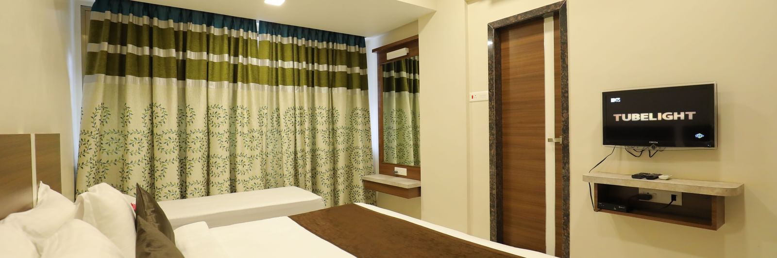 The queen size bed in the Deluxe Room of Highland Resort facing the wall-mounted TV.