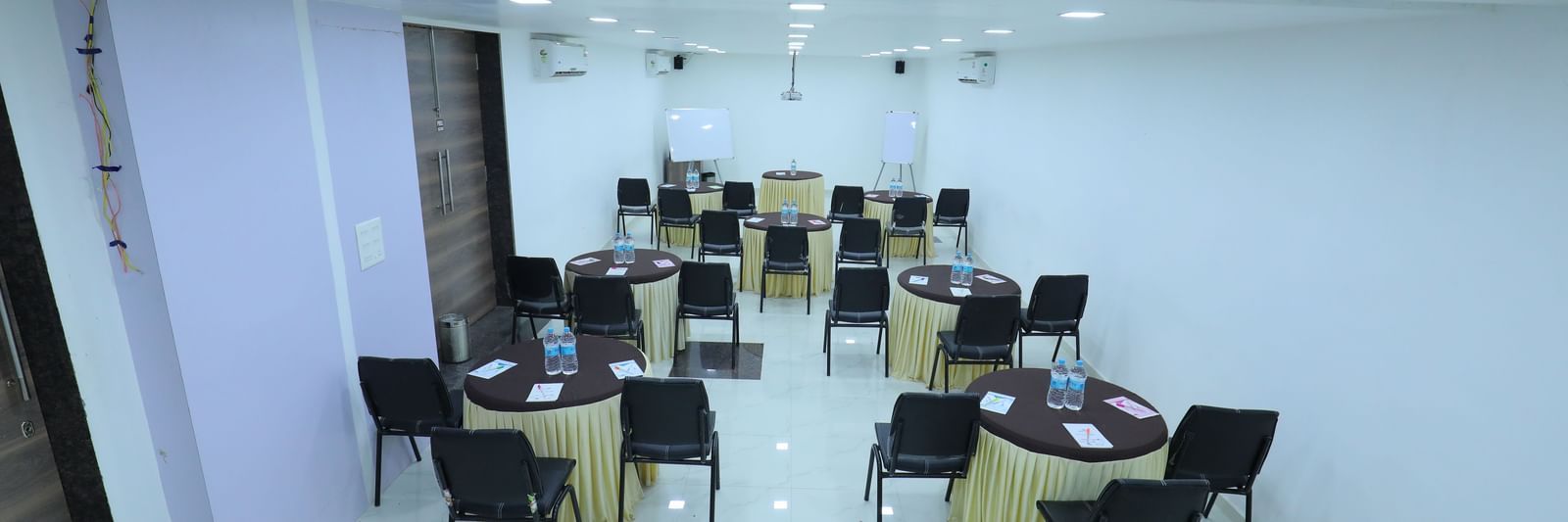 Round tables covered with table cloth, with chairs, water bottles, additional stationary, in the Regency banquet hall of Highland Resort.