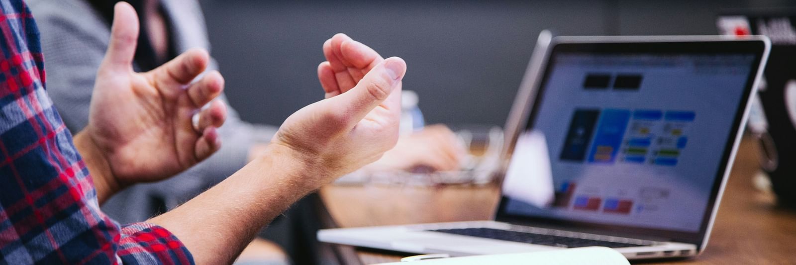 An image of a person enacting something in a meeting room with laptop placed on the table - Kamats India