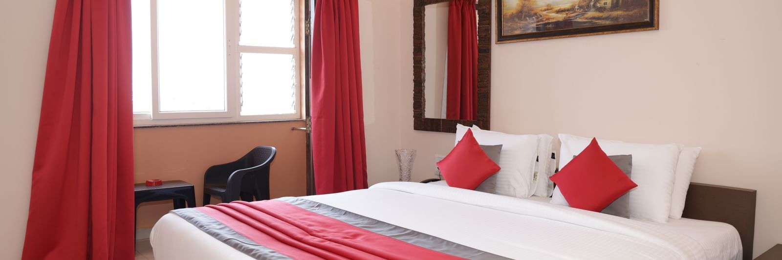 A bed placed near a window with curtains, wall art, bedside tables at Nazri The Verda Hotel, Arambol.