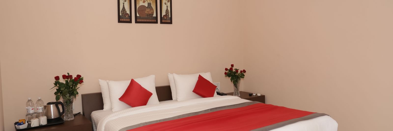 A bedroom at Nazri The Verda Hotel, Arambol, featuring a bed with cushions, bedside tables, and wall decorations.