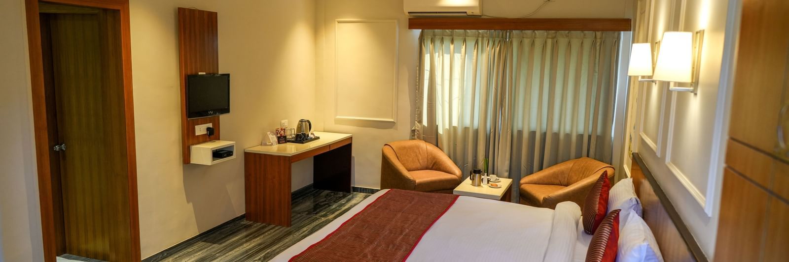 Well-appointed guest room with a king-size bed and seating for relaxation at Pravasa Hotel Kolhapur.