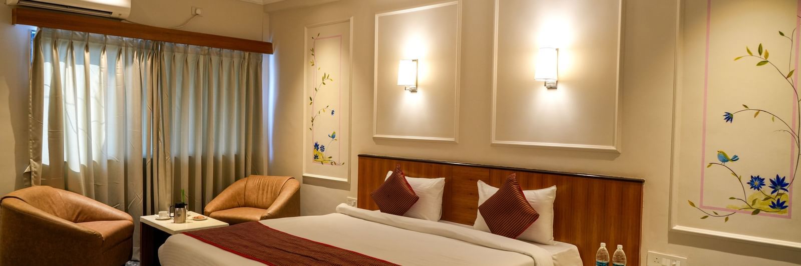 Stylish guest room with a double bed, seating area, and soft lighting at Pravasa Hotel Kolhapur.