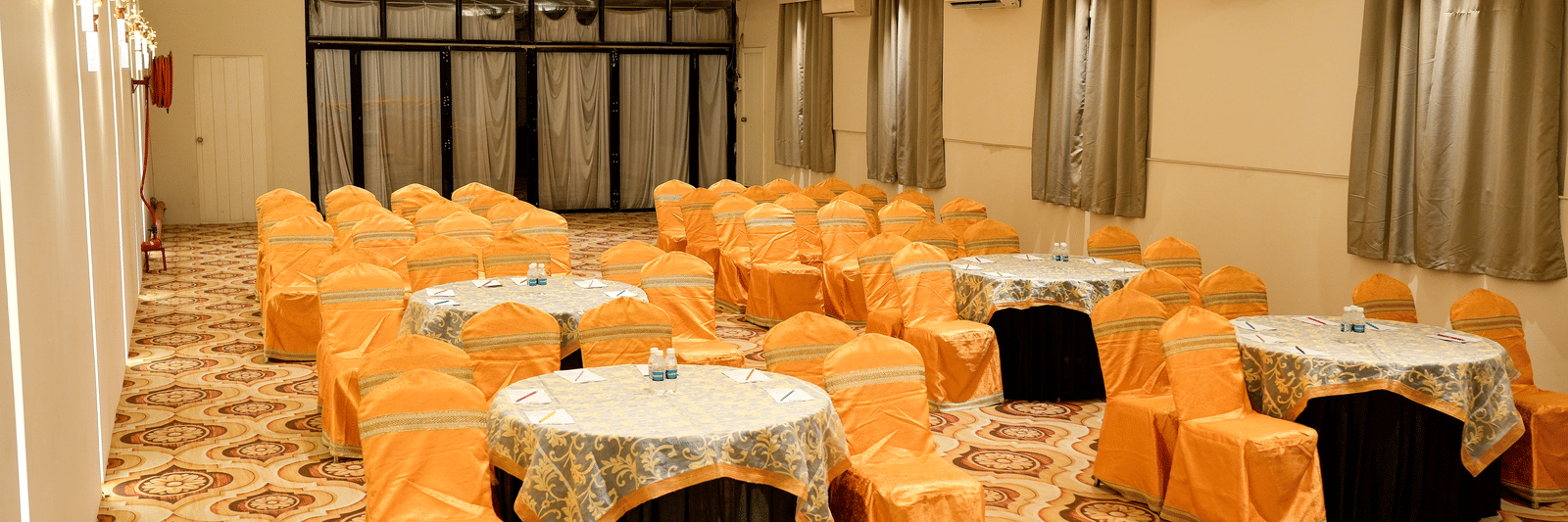 Banquet hall with tables and chairs arranged for dining at Pravasa Hotel, Kolhapur.