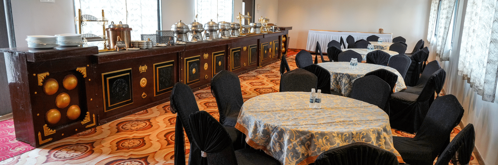 Dining area with tables and buffet counter at Pravasa Hotel, Kolhapur.