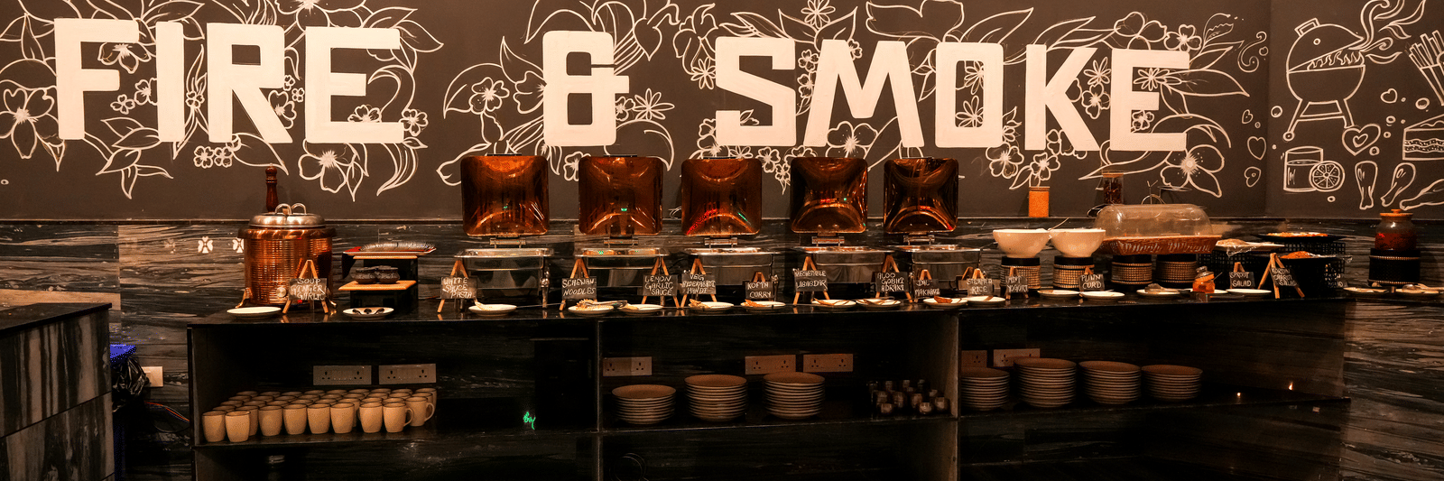 Restaurant buffet counter with “Fire & Smoke” sign at Pravasa Hotel, Kolhapur.