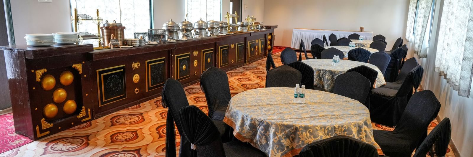 Banquet hall with round tables and elegant seating for gatherings at Pravasa Hotel Kolhapur.