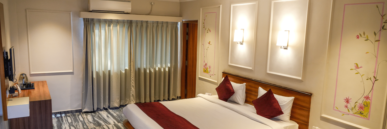  A well-designed deluxe bedroom with striking black and white patterned flooring and recessed wall lights at Pravasa Hotel, Kolhapur. 